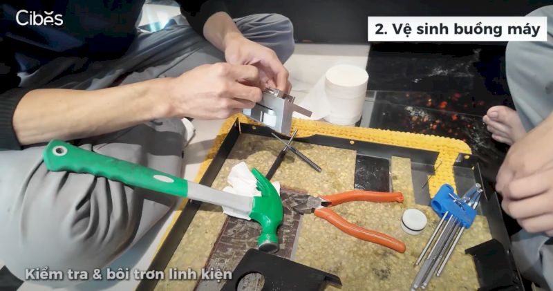 Kỹ thuật viên đang vệ sinh linh kiện thang máy bằng dầu chuyên dụng chính hãng
